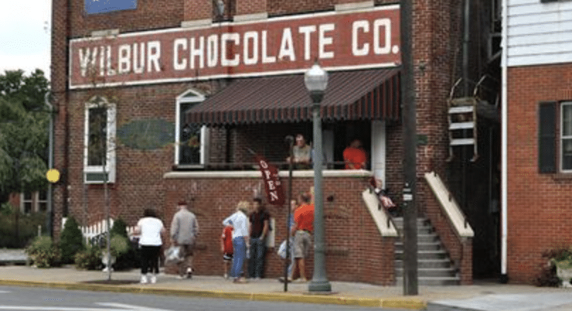 Wilbur Chocolate Co, an old brown brick building with people lined up outside on the sidewalk