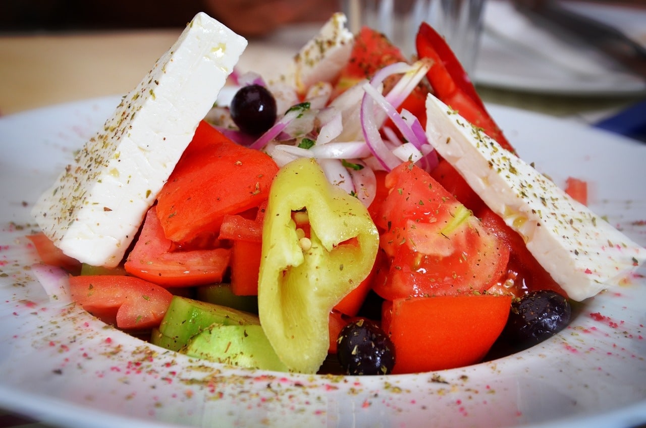Greek salad with feta, red peppers, banan peppers, tomatoes and onions on a plate