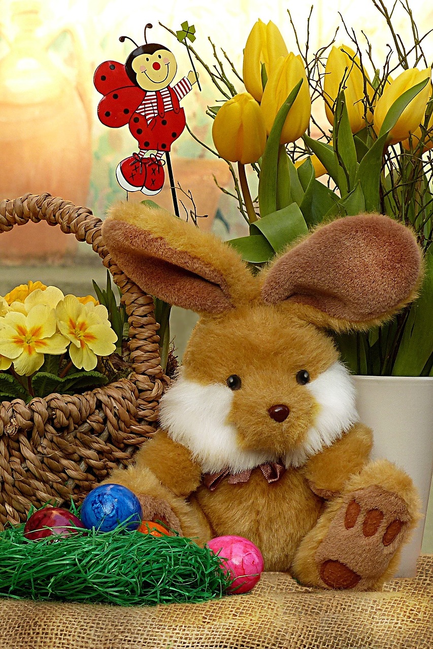 Stuffed toy Easter Bunny by a basket of yellow flowers