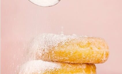 a spoonful of sugar poured over a stack of three fastnachts